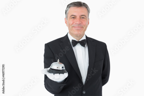 Photo: Man in suit holding hotel bell Man in suit holding hotel bell