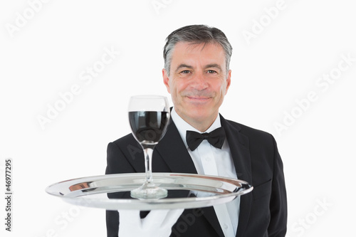 Photo: Smiling waiter holding a glass of wine on a silver tray Smiling waiter holding a glass of wine on a silver tray