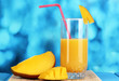 Ripe appetizing mango on woven napkin on blue background