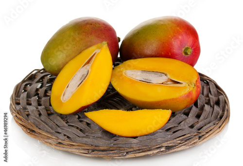Photo: Ripe appetizing mango on wicker cradle isolated on white Ripe appetizing mango on wicker cradle isolated on white