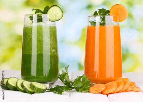 Photo: Fresh vegetable juices on wooden table, on green background Fresh vegetable juices on wooden table, on green background