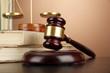 Golden scales of justice, gavel and books on brown background