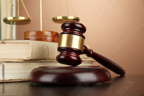 Photo: Golden scales of justice, gavel and books on brown background Golden scales of justice, gavel and books on brown background