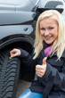 Frau misst Reifenprofil eines Autoreifen