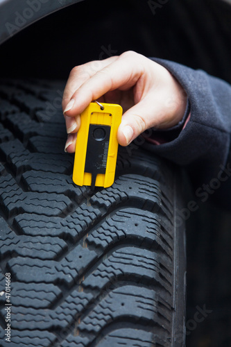 Photo: Frau misst Reifenprofil eines Autoreifen Frau misst Reifenprofil eines Autoreifen
