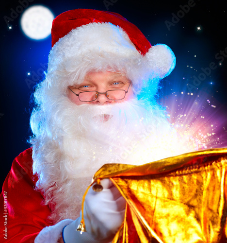 Photo: Christmas Santa. Santa Claus opening Magic Bag with Gifts Christmas Santa. Santa Claus opening Magic Bag with Gifts