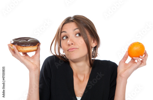Photo: Woman comparing unhealthy donut and orange fruit Woman comparing unhealthy donut and orange fruit