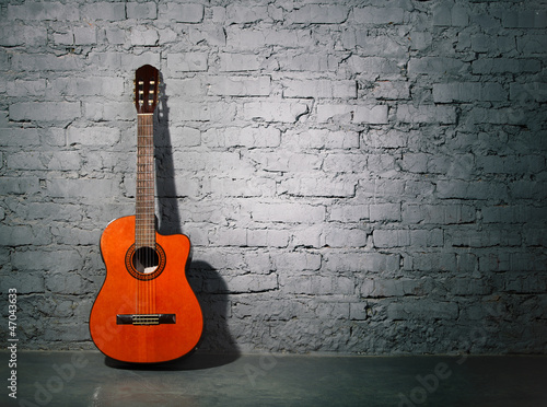 Photo: Acoustic guitar leaning on grungy wall Acoustic guitar leaning on grungy wall