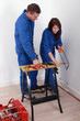 Worker showing an apprentice how to use a hacksaw