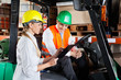 Photo: Supervisor Showing Clipboard To Colleague Sitting In Forklift Supervisor Showing Clipboard To Colleague Sitting In Forklift