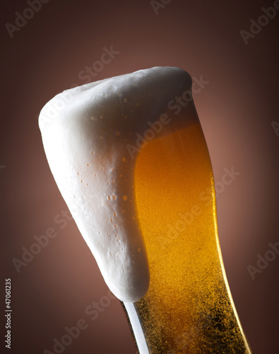 Photo: full glass of beer on a brown full glass of beer on a brown