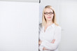 junge frau im büro steht neben flipchart