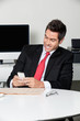 Businessman Using Cell Phone At Desk