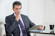 Contemplative Businessman Using Digital Tablet In Office