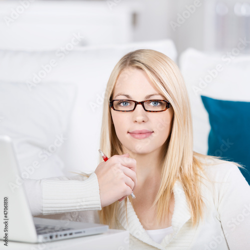Photo: blonde frau sitzt mit laptop auf dem sofa blonde frau sitzt mit laptop auf dem sofa