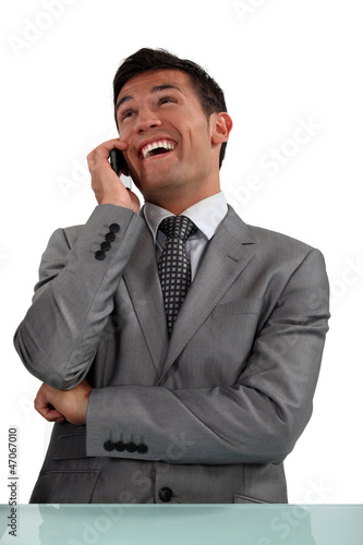 Photo: A businessman laughing over the phone. A businessman laughing over the phone.