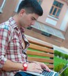 Young man with a laptop on the bench.