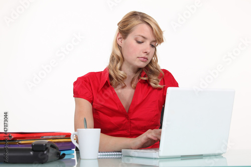 Photo: Bored secretary typing on her laptop Bored secretary typing on her laptop