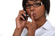 Black businesswoman making hush gesture during phone call