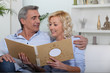 couple sitting on sofa skimming through family album