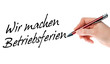 Hand mit Stift schreibt Wir machen Betriebsferien