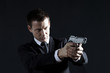 Secret agent aiming with gun against black background