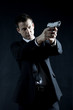 Secret agent aiming with gun against black background