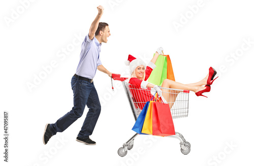 Photo: Guy pushing a woman in christmas costume with bags in a cart Guy pushing a woman in christmas costume with bags in a cart