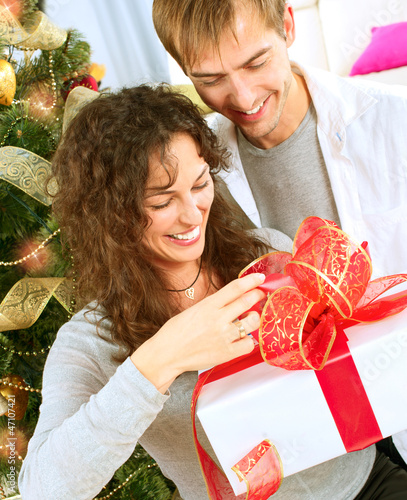 Photo: Happy Couple Opening Christmas Gift. Christmas Family Happy Couple Opening Christmas Gift. Christmas Family