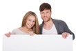 Positive young couple with blank board