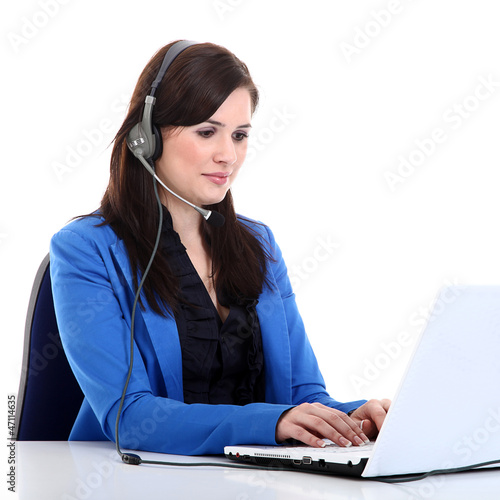 Photo: Junge Büro Frau mit Headset nimmt Daten am Laptop auf Junge Büro Frau mit Headset nimmt Daten am Laptop auf