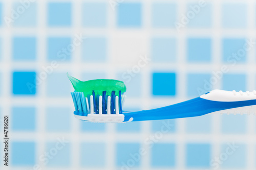 Photo: toothbrush against blue tile background toothbrush against blue tile background