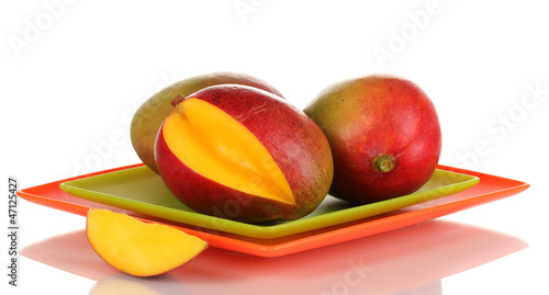 Photo: Ripe appetizing mango on red plate isolated on white Ripe appetizing mango on red plate isolated on white
