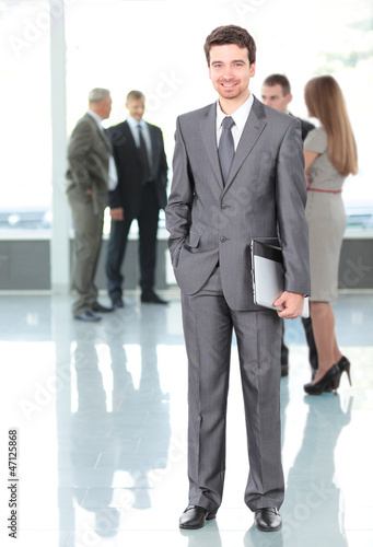 Photo: Happy smart business man with team in the background Happy smart business man with team in the background