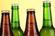 Coloured glass beer bottles on yellow background