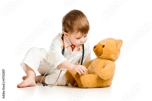 Photo: Adorable child with clothes of doctor and teddy bear over white Adorable child with clothes of doctor and teddy bear over white