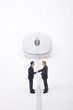 Photo: Businessman figurines shaking hands against mouse in background Businessman figurines shaking hands against mouse in background