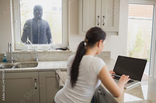 Photo: Woman being observed by burglar through window Woman being observed by burglar through window