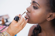 Woman sitting getting lip-glosss put on