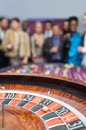 Photo: People standing looking at the roulette wheel People standing looking at the roulette wheel