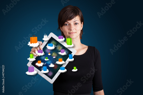 Photo: woman holding modern tablet with colorful shopping bags on cloud woman holding modern tablet with colorful shopping bags on cloud