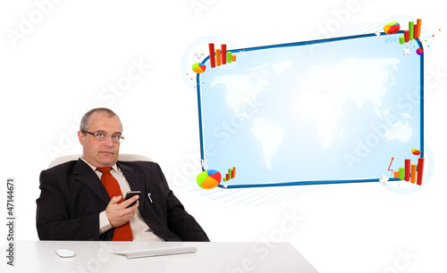 Photo: Businessman sitting at desk and holding a mobilephone with copy Businessman sitting at desk and holding a mobilephone with copy