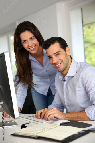 Photo: Young office workers in front of desktop computer Young office workers in front of desktop computer