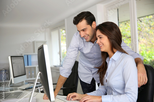 Photo: Young office workers in front of desktop computer Young office workers in front of desktop computer