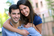 Cheerful young man carrying girlfriend on his back