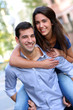 Cheerful young man carrying girlfriend on his back