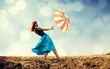 Redhead girl with umbrella at windy field.