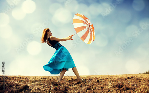 Photo: Redhead girl with umbrella at windy field. Redhead girl with umbrella at windy field.