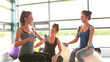Women lifting weights on exercise ball with trainer
