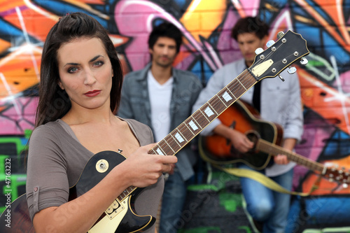 Photo: Female guitarist standing with band members Female guitarist standing with band members